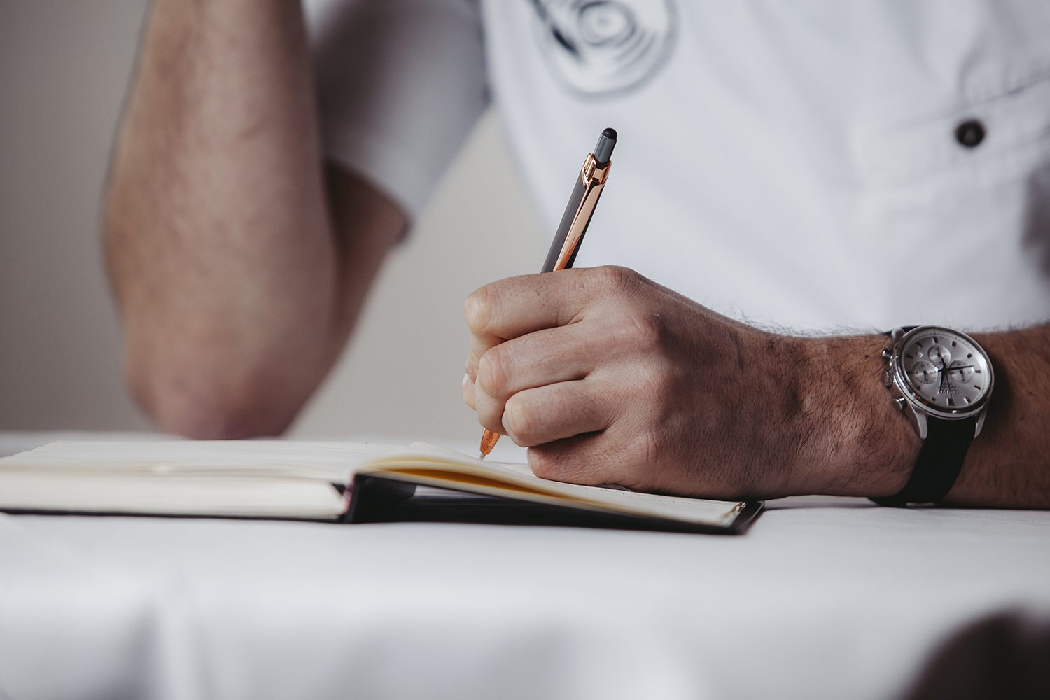 foto van handen van chef-kok die schrijft in zijn notitieboek